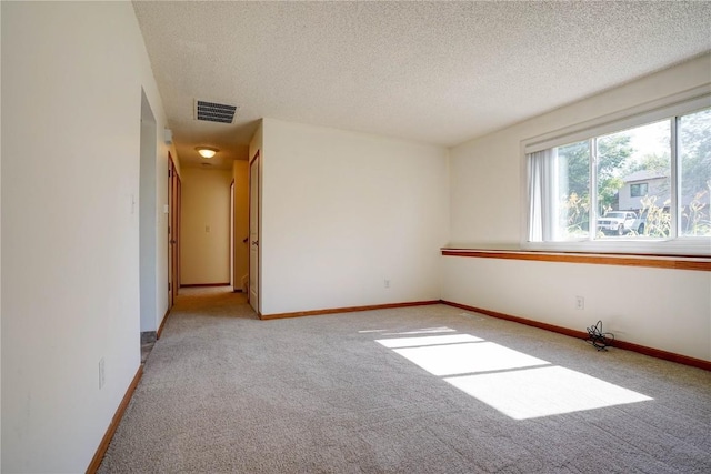 unfurnished room featuring a textured ceiling and light colored carpet