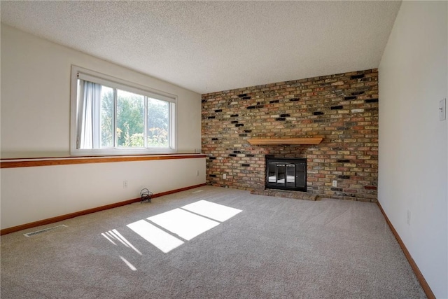 unfurnished living room featuring carpet flooring, a textured ceiling, and a brick fireplace