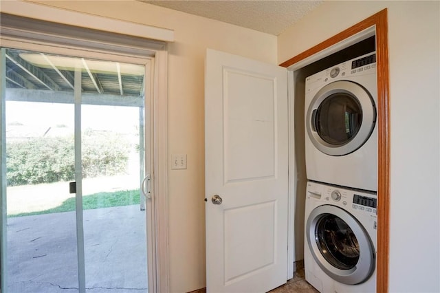 clothes washing area featuring a textured ceiling and stacked washer / dryer