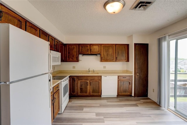 kitchen featuring a textured ceiling, sink, light hardwood / wood-style floors, and white appliances