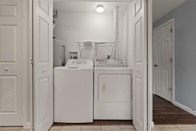 laundry area with washer and clothes dryer and light tile patterned floors