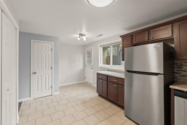 kitchen with stainless steel fridge, dark brown cabinetry, light tile patterned floors, and backsplash