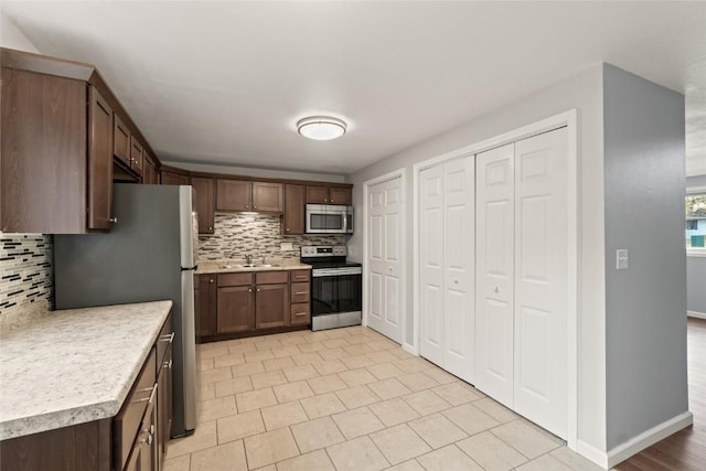 kitchen featuring sink, dark brown cabinetry, backsplash, and appliances with stainless steel finishes