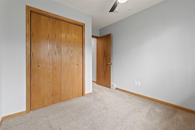 unfurnished bedroom featuring ceiling fan, a closet, and light carpet