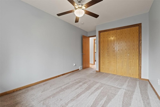 unfurnished bedroom with light colored carpet, a closet, and ceiling fan