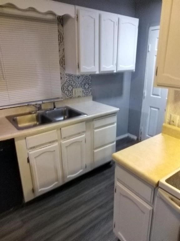 kitchen with white cabinets, dark hardwood / wood-style flooring, sink, and black dishwasher