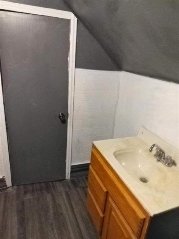 bathroom with hardwood / wood-style floors, vanity, and vaulted ceiling