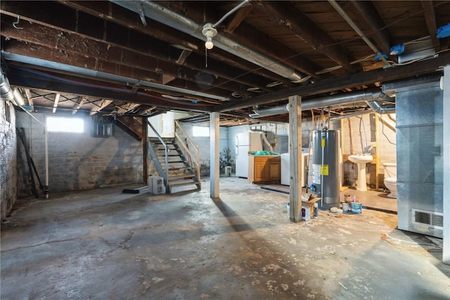 basement featuring washer / clothes dryer, sink, white fridge, and gas water heater