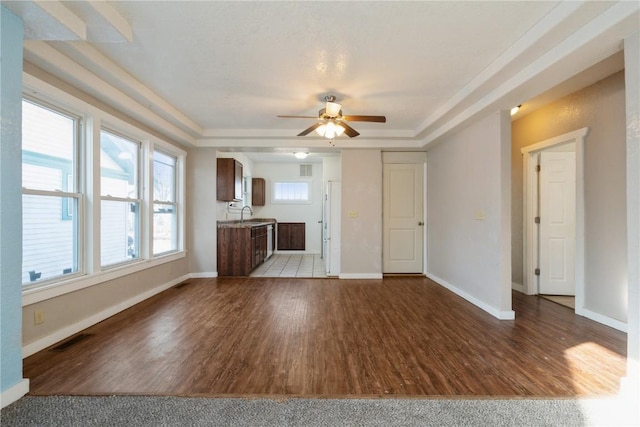 unfurnished living room featuring a tray ceiling, ceiling fan, light hardwood / wood-style floors, and sink