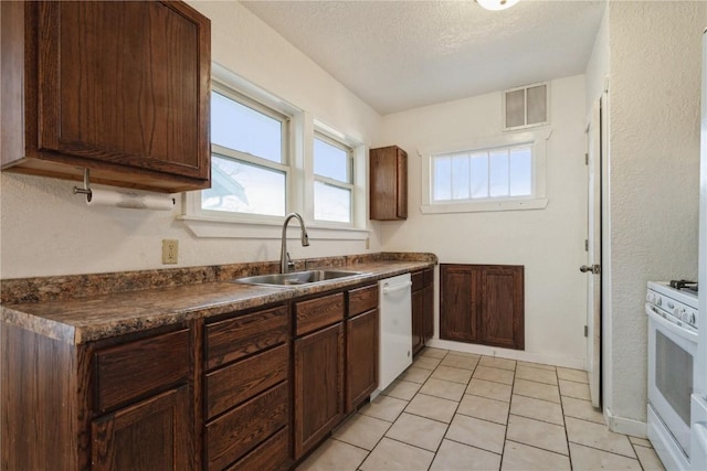 kitchen featuring a textured ceiling, dark brown cabinets, white appliances, and sink