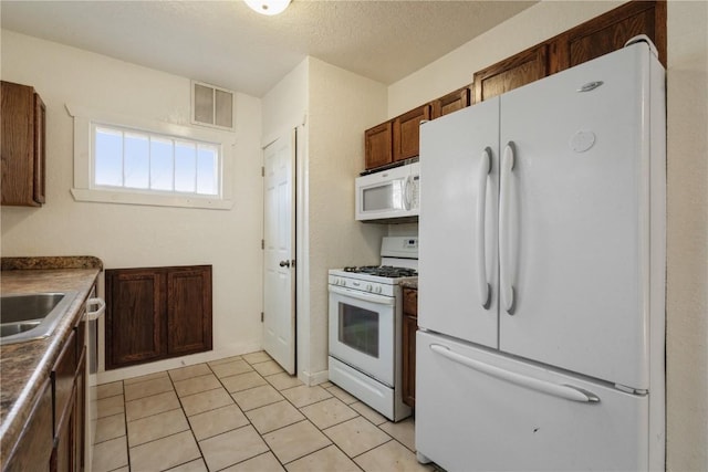 kitchen featuring light tile patterned floors, white appliances, a textured ceiling, and sink