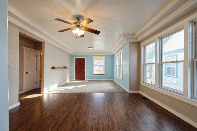 unfurnished living room featuring a textured ceiling, dark hardwood / wood-style flooring, a raised ceiling, and ceiling fan