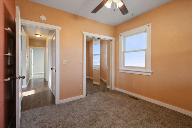 unfurnished bedroom featuring a closet, dark carpet, and ceiling fan