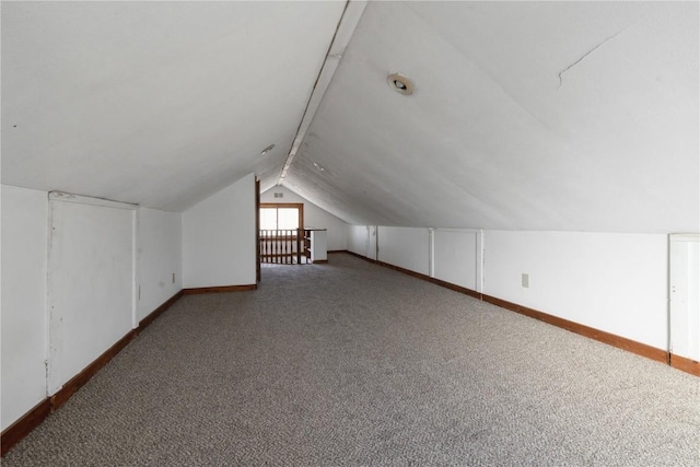 additional living space with dark carpet and vaulted ceiling