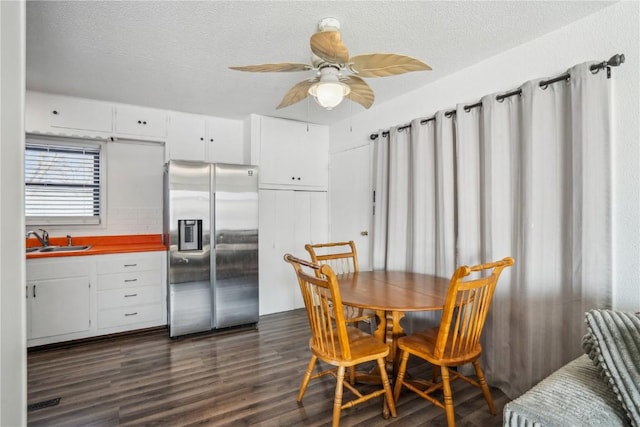 dining area with dark hardwood / wood-style flooring, ceiling fan, sink, and a textured ceiling