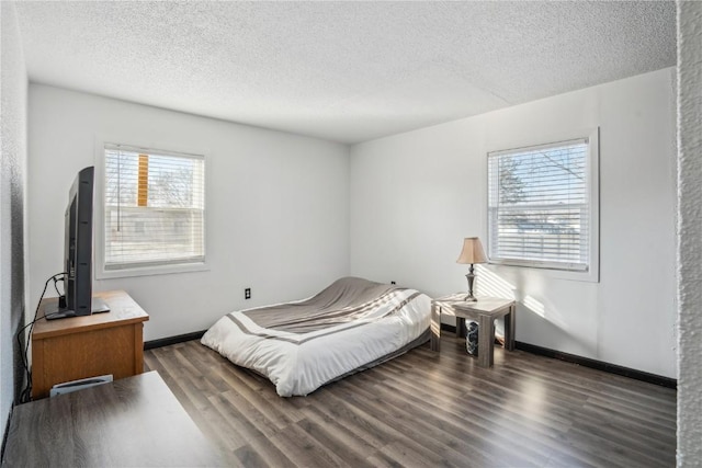 bedroom featuring multiple windows, dark hardwood / wood-style flooring, and a textured ceiling