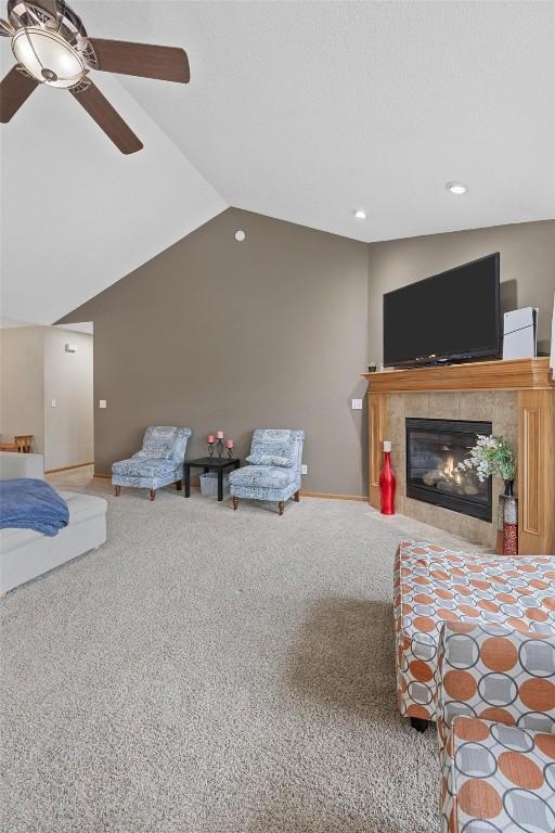 carpeted bedroom with ceiling fan, a tile fireplace, and vaulted ceiling