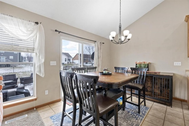 dining space featuring vaulted ceiling, light tile patterned floors, and an inviting chandelier