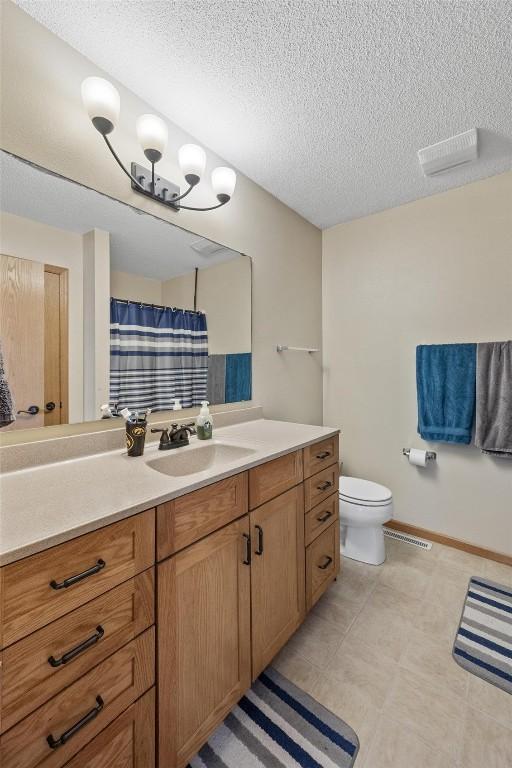 bathroom with curtained shower, vanity, a textured ceiling, and toilet