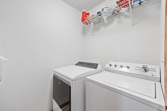 laundry room with washing machine and clothes dryer and a textured ceiling