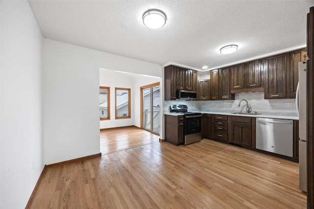 kitchen with sink, light hardwood / wood-style flooring, a textured ceiling, appliances with stainless steel finishes, and dark brown cabinets