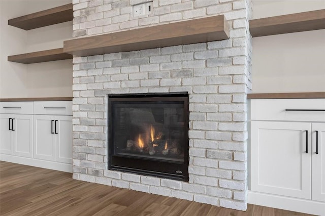 details with hardwood / wood-style floors and a brick fireplace