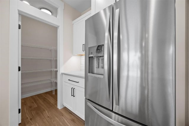 kitchen with white cabinets, stainless steel fridge, and light wood-type flooring