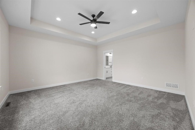 carpeted spare room with ceiling fan and a tray ceiling