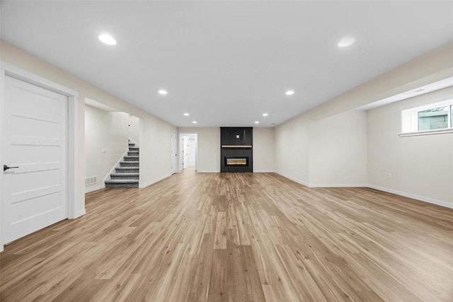 basement featuring a large fireplace and light hardwood / wood-style floors