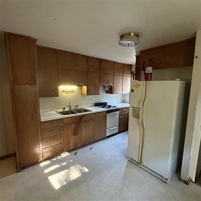 kitchen with range, white fridge with ice dispenser, and sink