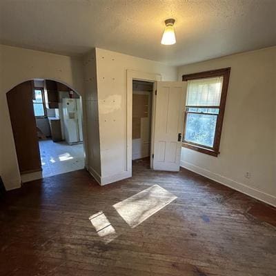 unfurnished bedroom featuring a textured ceiling, white refrigerator, a closet, and multiple windows