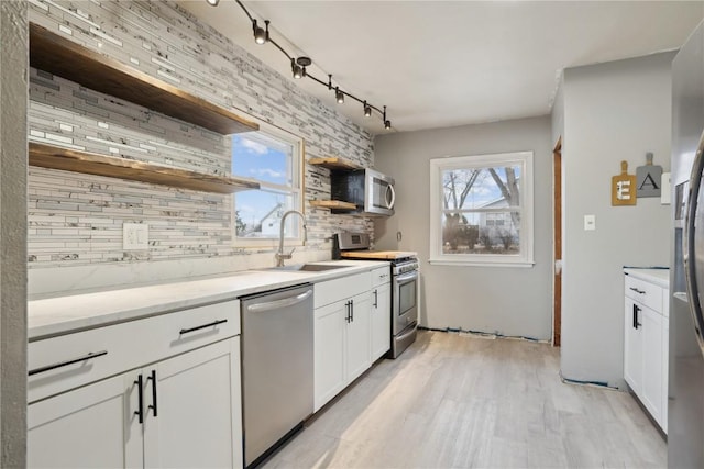 kitchen featuring white cabinetry, sink, stainless steel appliances, tasteful backsplash, and light hardwood / wood-style floors