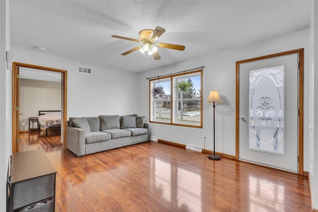 living room featuring hardwood / wood-style floors, a textured ceiling, and ceiling fan