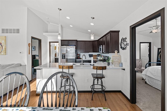 kitchen with dark brown cabinetry, stainless steel appliances, ceiling fan, sink, and lofted ceiling