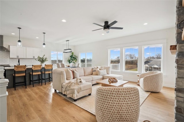 living room with ceiling fan, light hardwood / wood-style flooring, and a healthy amount of sunlight