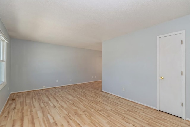 empty room with a textured ceiling and light wood-type flooring