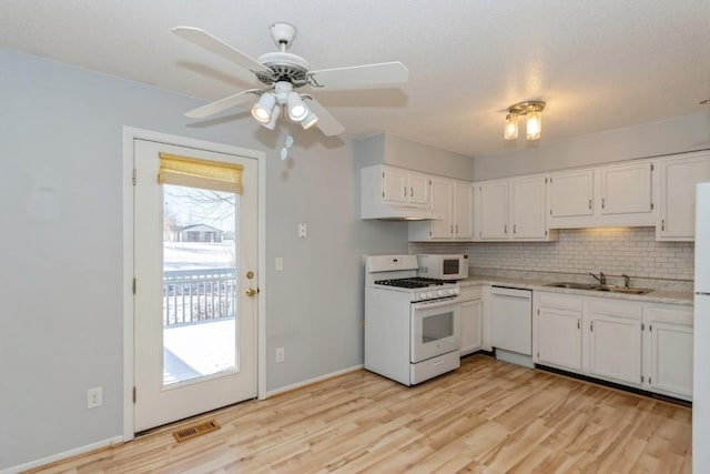 kitchen with white appliances, sink, decorative backsplash, light hardwood / wood-style floors, and white cabinetry