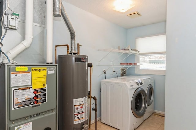 laundry area with washer and dryer, light tile patterned floors, and water heater