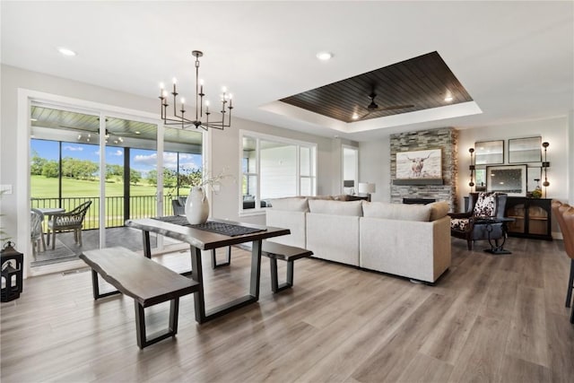 dining area with a tray ceiling, wood-type flooring, and ceiling fan with notable chandelier