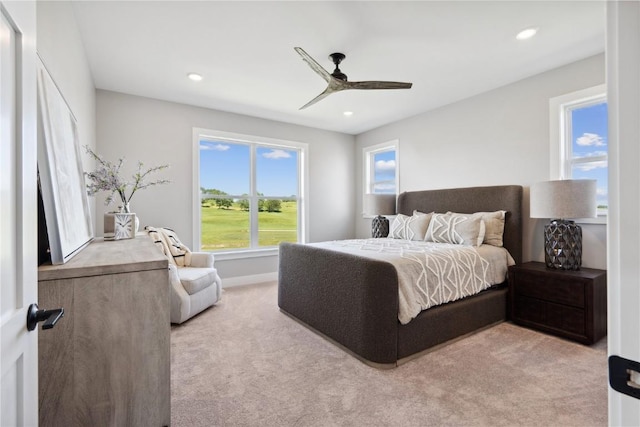 carpeted bedroom featuring multiple windows and ceiling fan