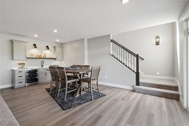 dining area with light hardwood / wood-style floors, wet bar, and wine cooler