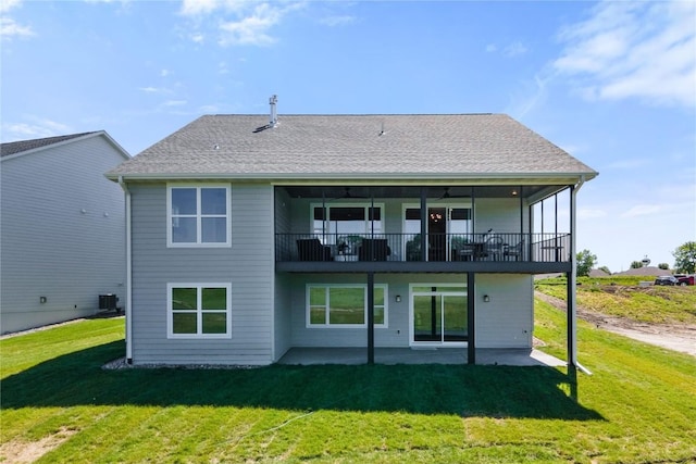 rear view of property featuring a yard, a balcony, central AC unit, and a patio area