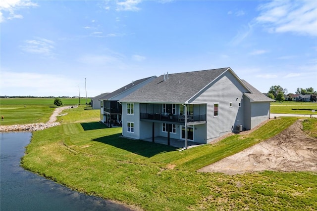 rear view of house with a lawn and a deck with water view