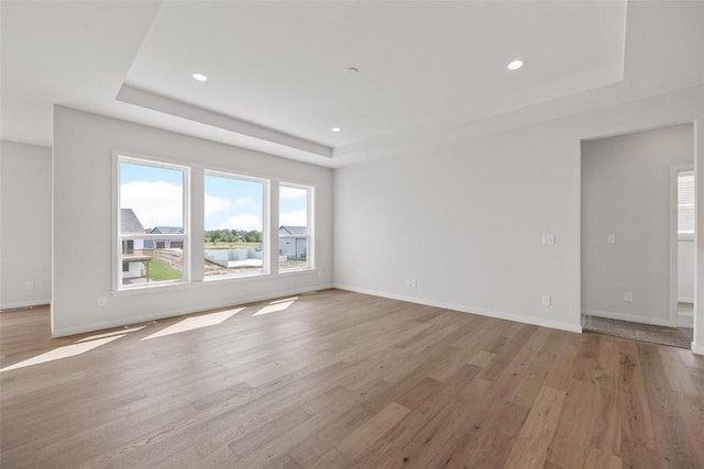 unfurnished living room featuring a tray ceiling and light hardwood / wood-style floors