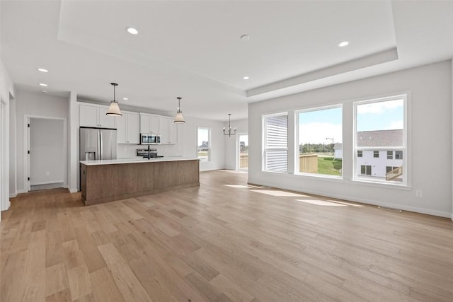 kitchen featuring white cabinets, stainless steel appliances, a raised ceiling, and a spacious island