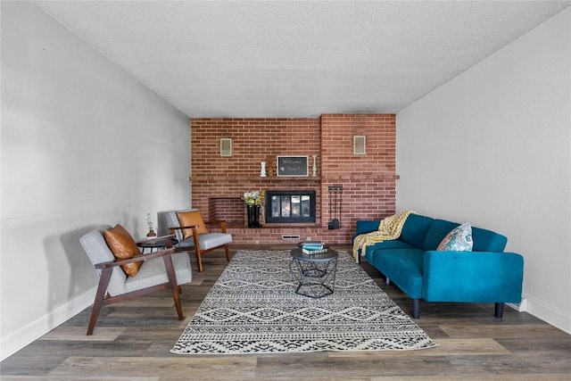 living room featuring a brick fireplace, a textured ceiling, and hardwood / wood-style floors