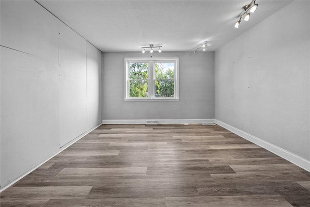 spare room featuring rail lighting and hardwood / wood-style floors