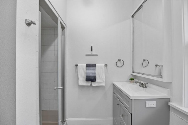 bathroom featuring a shower with shower door and vanity