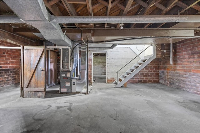 basement featuring heating unit and brick wall