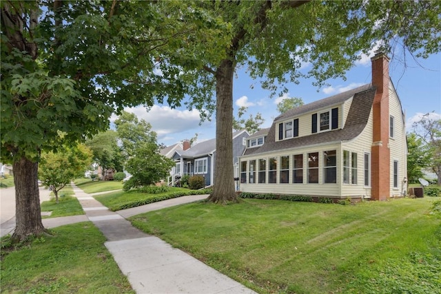 view of front facade with a sunroom and a front lawn